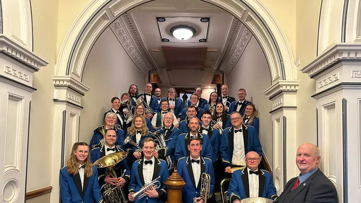 The contesting band in uniform, holding their instruments.