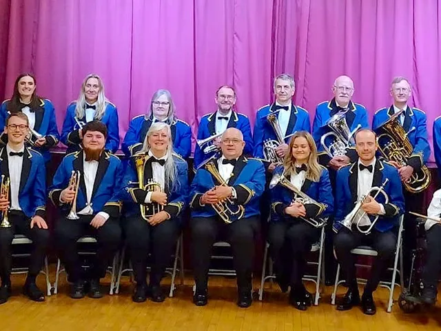 The members of Garforth Brass in uniform, gathered on stage.