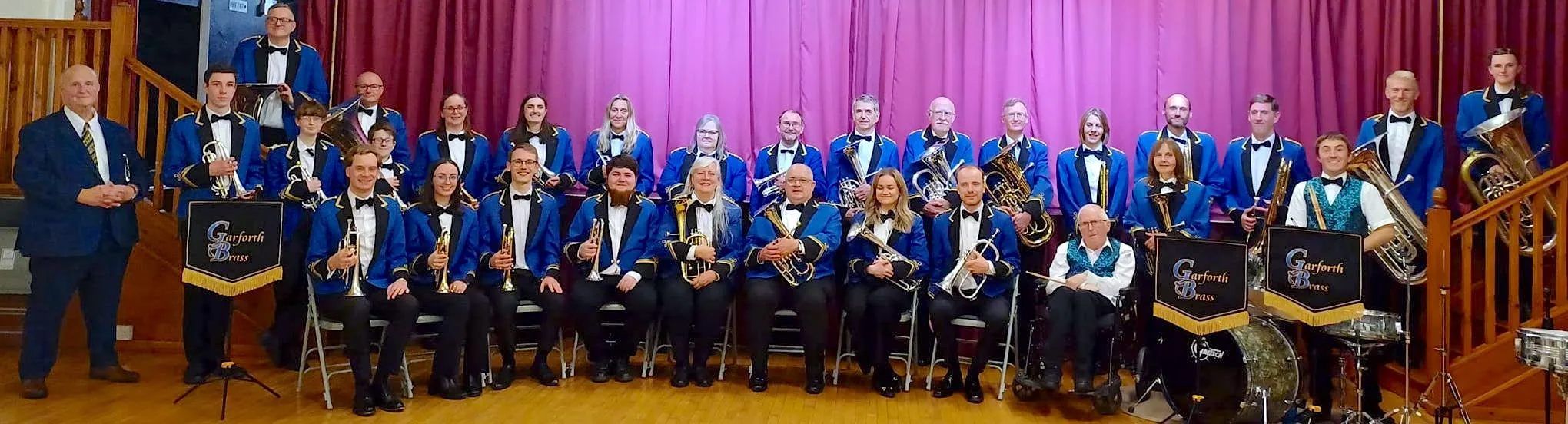 The members of Garforth Brass in uniform, gathered on stage.